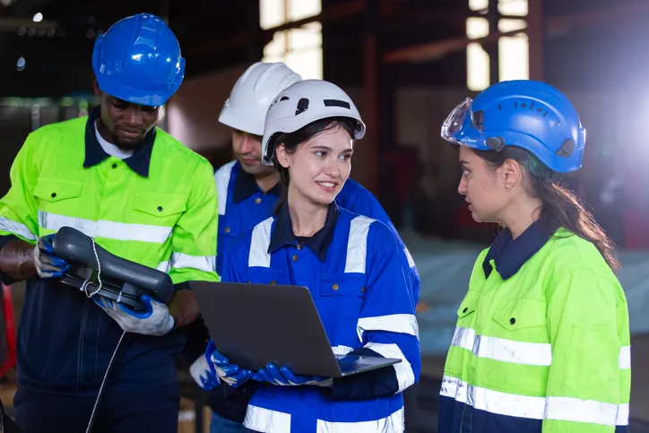 jovenes adultos con uniforme de trabajo y cascos en industria