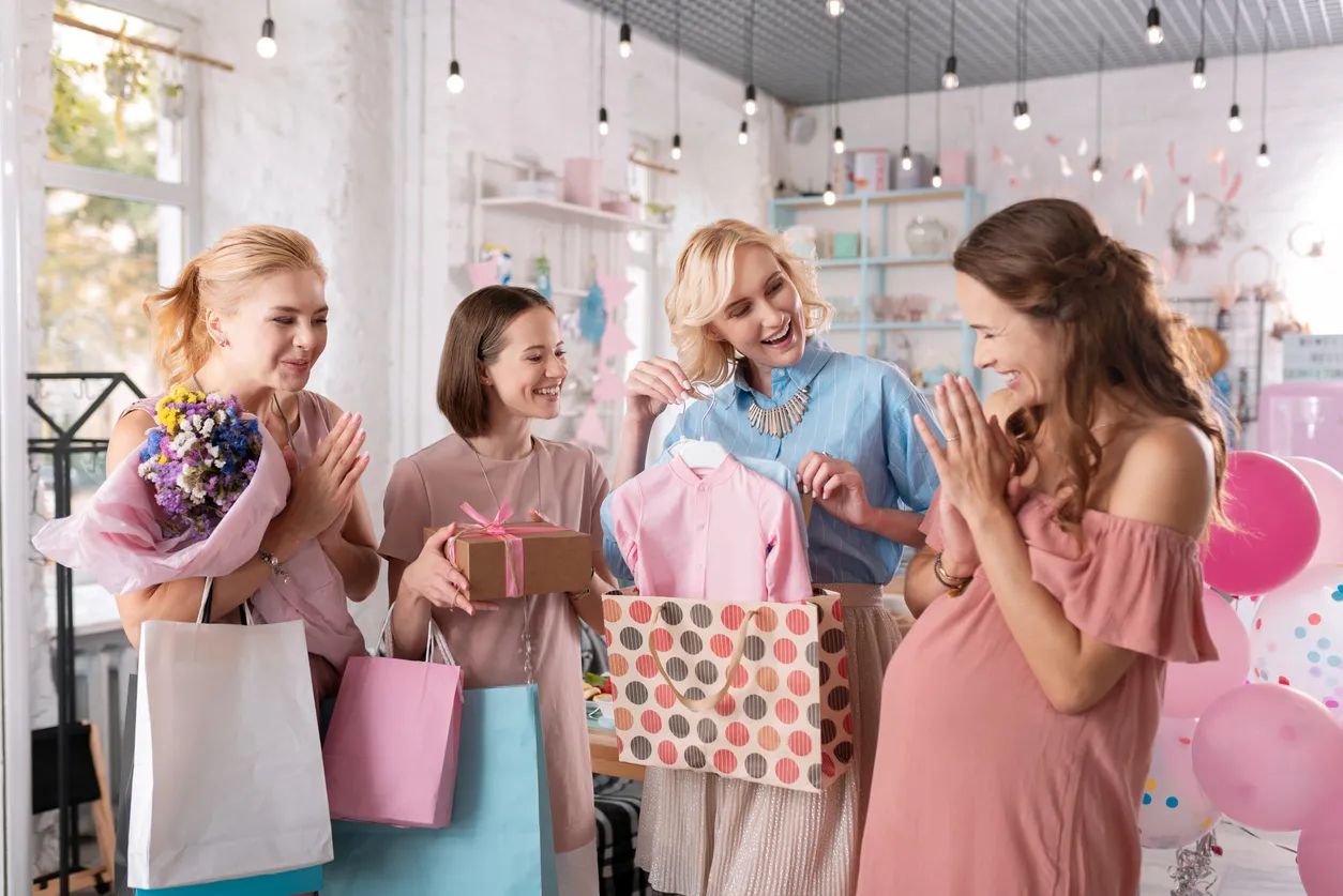 Grupo de mujeres en baby shower abriendo los regalos de bebé