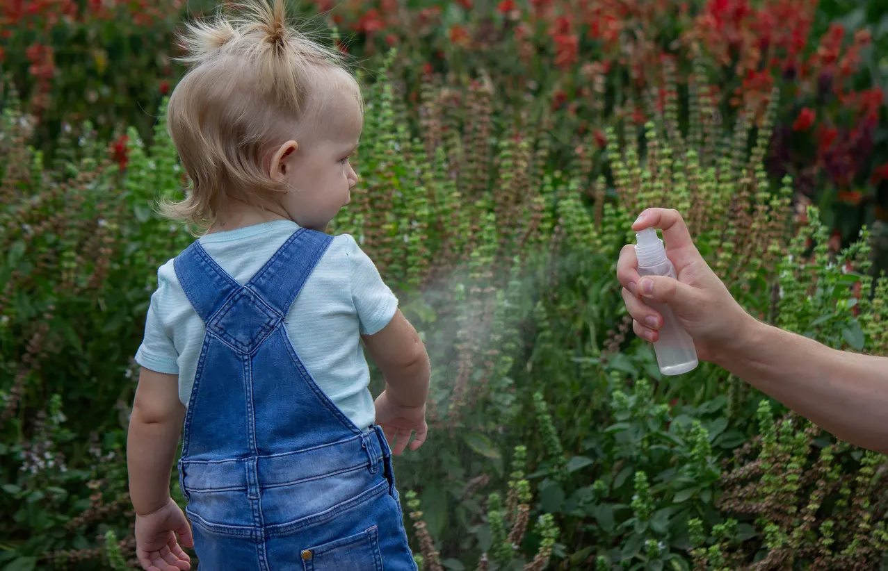 La madre aplica un aerosol contra insectos en el cuerpo del niño.