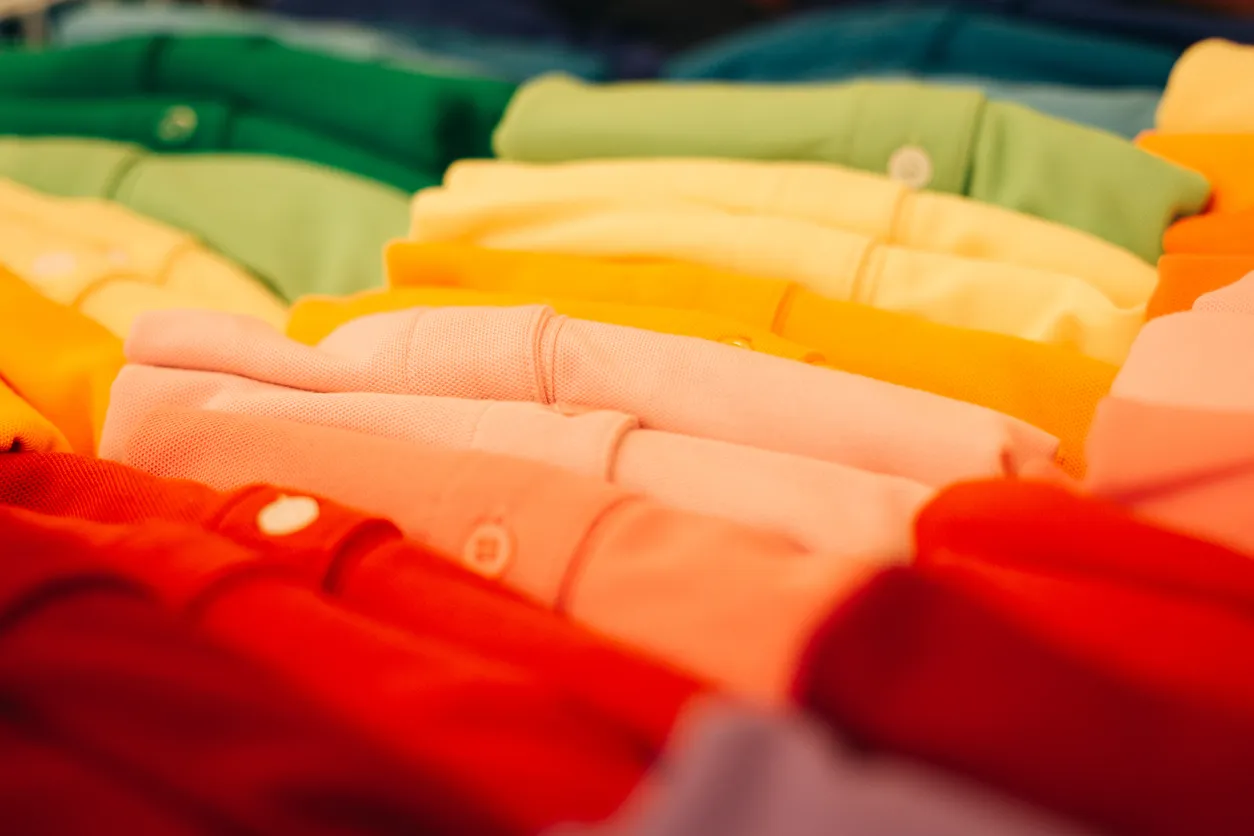 Playeras polo de colores para uniformes acomodadas de forma ordenada. 