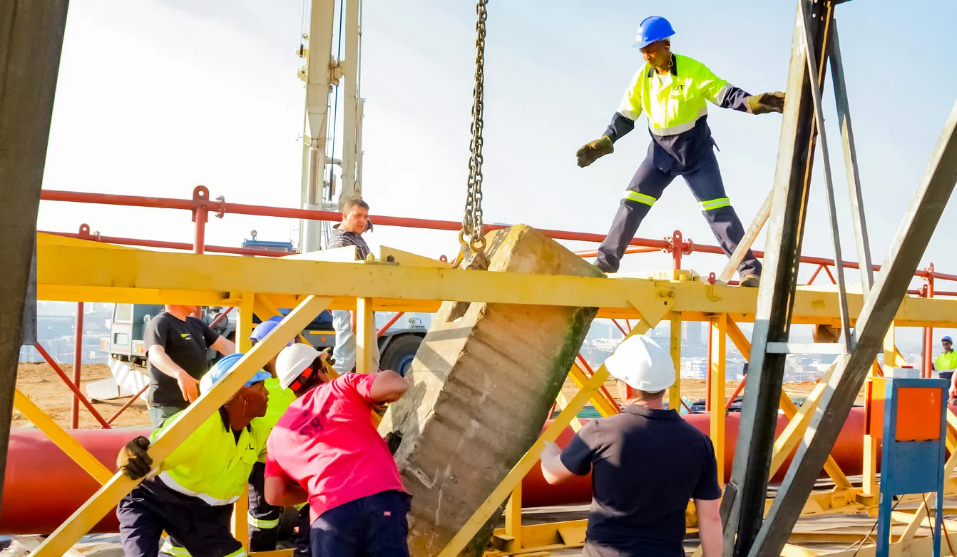 Varios trabajadores con equipo de protección realizando el izaje de material