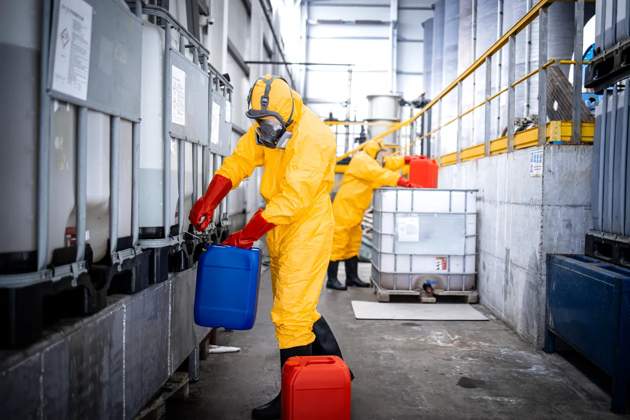 Trabajador llenando bidones con ácidos y productos químicos. La zeolita ayuda a la absorción y captura de gases