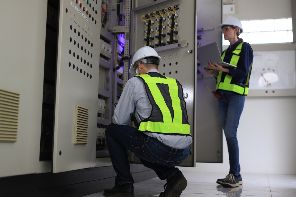 Dos ingenieros electricistas profesionales blancos caucásicos que trabajan con una computadora y una tableta digital 