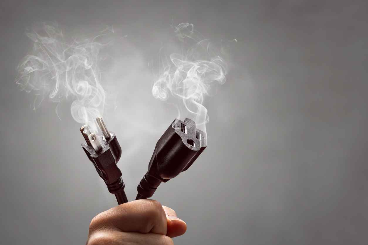 Mano sosteniendo los extremos humeantes de un cable de alimentación