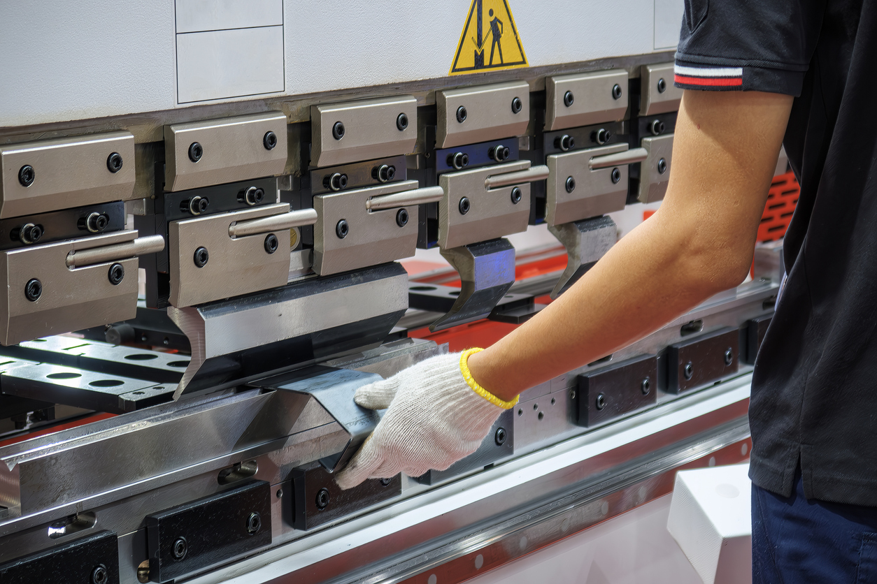 Cierre el operador de la máquina dobladora de prensas plegadoras, sostenga las piezas de chapa con un guante de seguridad