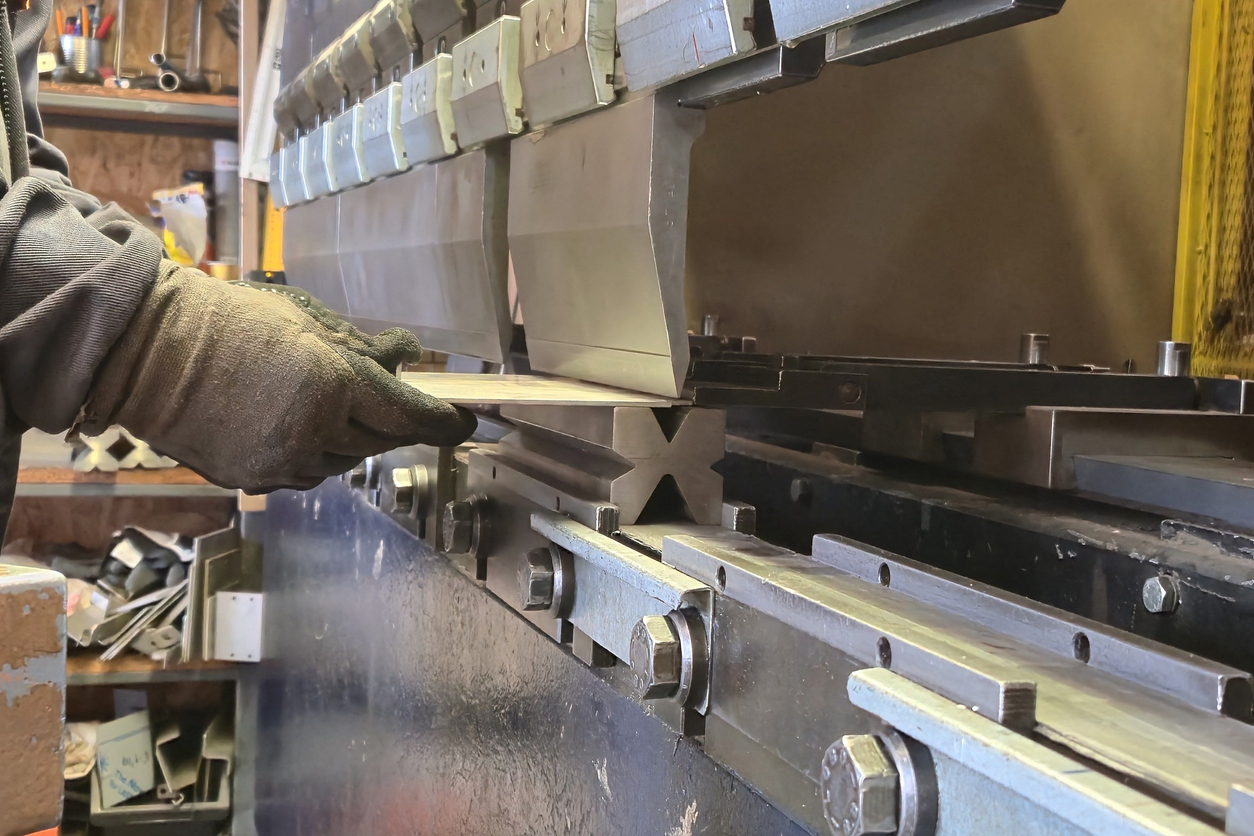 Un trabajador dobla una placa de acero en una máquina dobladora de láminas hidráulica