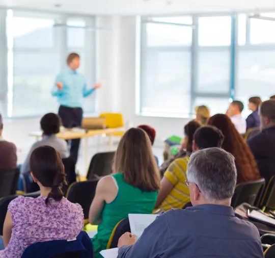 Persona dando curso de capacitación en una sala a un grupo de personas